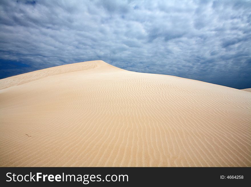 Wind on dunes - beautiful snd dune with dramatic cloudscape