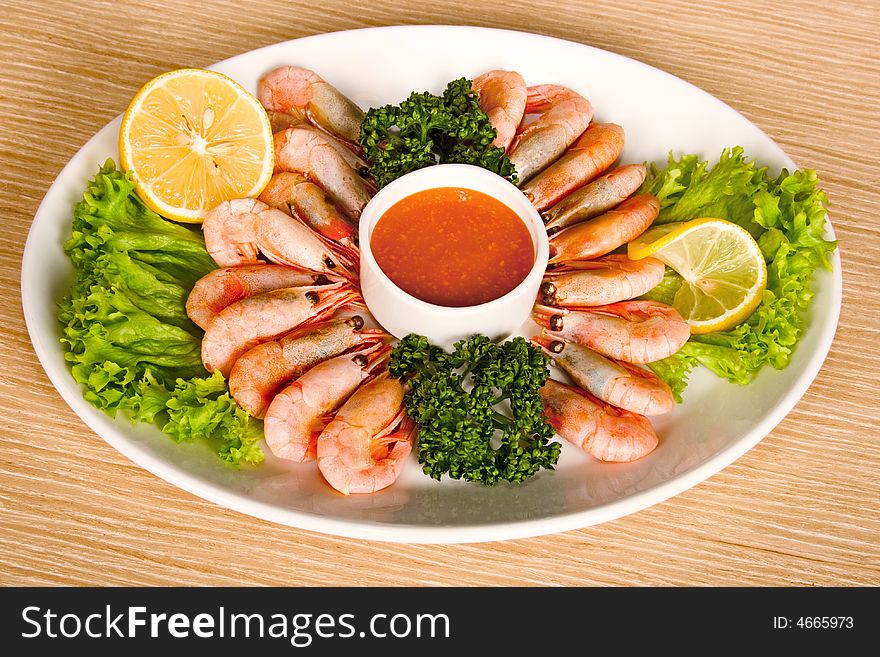 Shrimps with lemon, sauce and lettuce on table