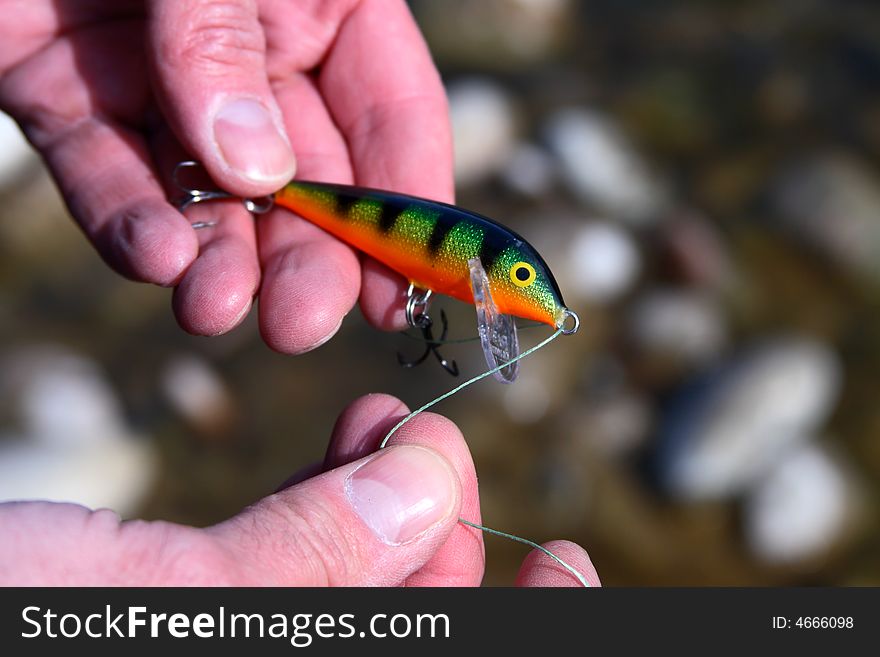 An angler tying on a fishing lure before hitting the river