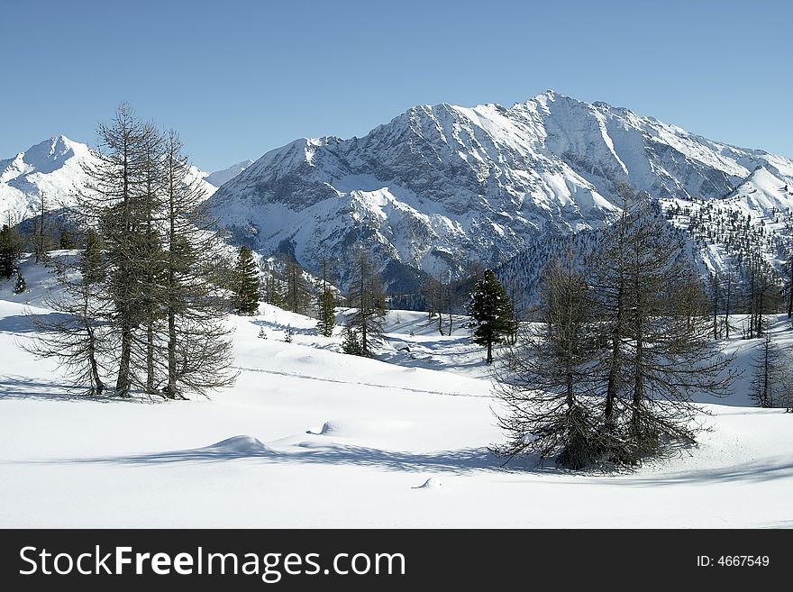 A snow covered meadow in the Italian Alps with craggy peaks in the background. A snow covered meadow in the Italian Alps with craggy peaks in the background.