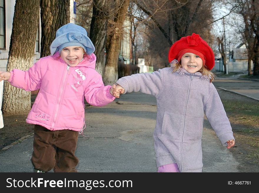 Merry running children holding hands and wearing hats. Merry running children holding hands and wearing hats