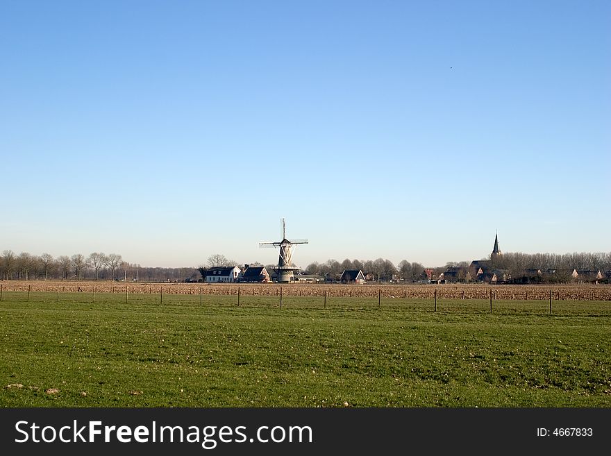 Typical Dutch landscape, including a traditional windmill and a small village with church tower