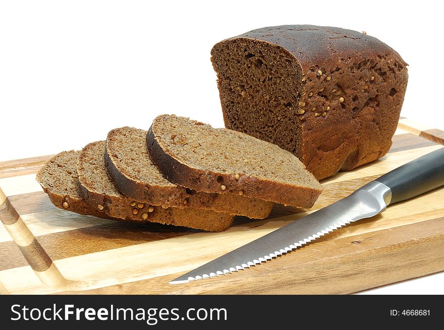 Loaf of sliced grain bread on wood bread board with knife isolated on white