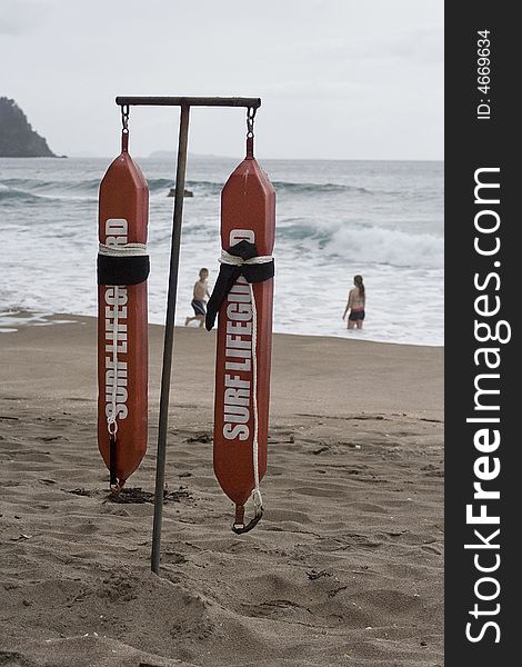 Surf lifeguard belts hanging with children playing in surf.