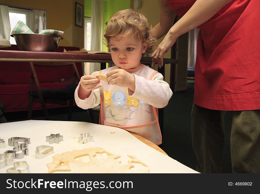 The child is helping mom to prepare the cookies. The child is helping mom to prepare the cookies.