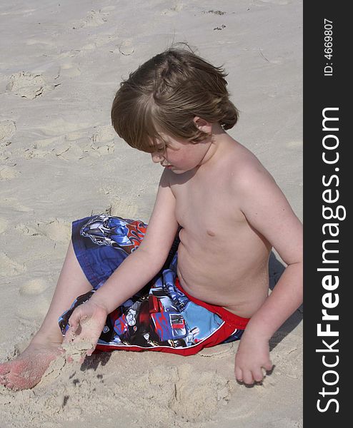 Young boy playing in sand on beach. Young boy playing in sand on beach