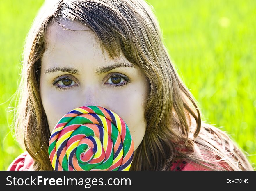 Blonde cutie behind spiral candy on green background. Blonde cutie behind spiral candy on green background