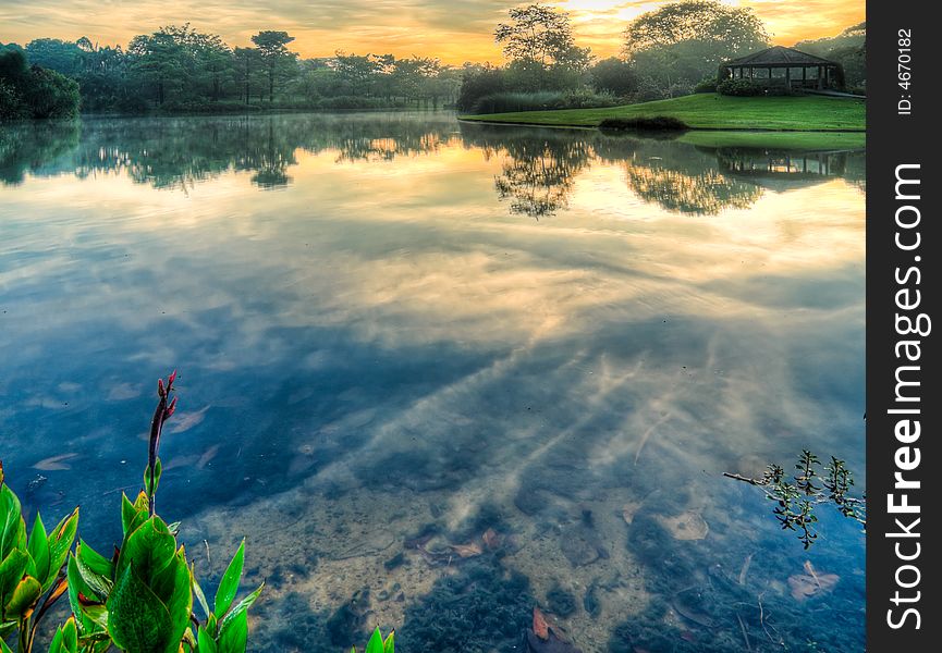 High altitude cirrus clouds at sunrise reflected in the shallow still lake. High altitude cirrus clouds at sunrise reflected in the shallow still lake