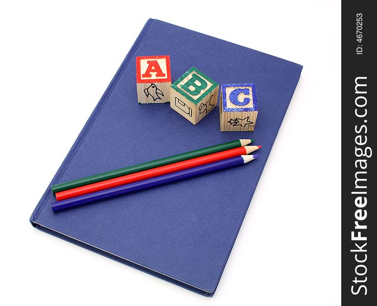 Alphabet blocks and colored pencils over a blue notebook. Alphabet blocks and colored pencils over a blue notebook