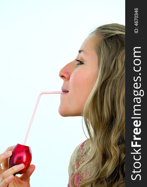 Pretty young woman drinking a juice of a red tropical fruit