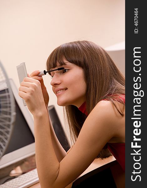 Young beautiful woman applying make-up at office. Young beautiful woman applying make-up at office