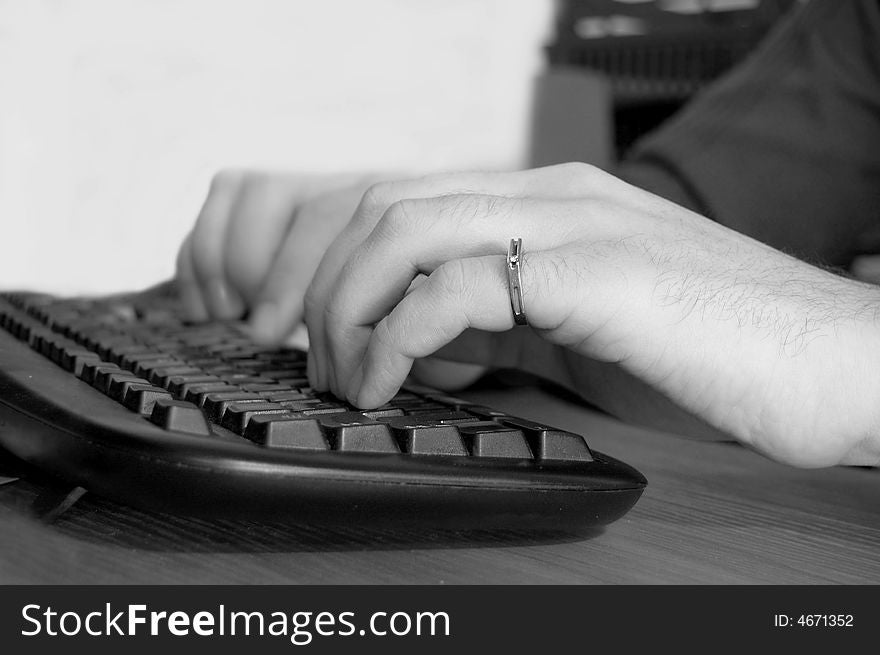 Male hands typing on keyboard, black and white image