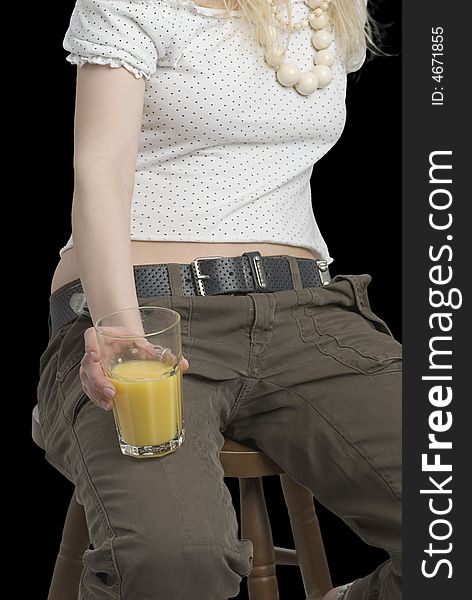 A glass of juice in the hand of young girl on the black background