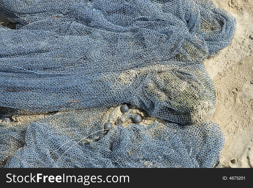 A blue industrial fishing net laying on the beach. A blue industrial fishing net laying on the beach.