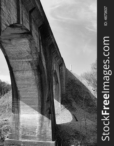 A black and white picture of a the underside of a bridge. A black and white picture of a the underside of a bridge