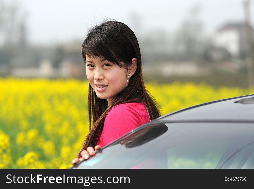 A girl is showing off beside someone's car. A girl is showing off beside someone's car.