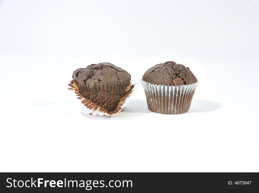 Two chocolate chip muffins in muffin cases with one muffin exposed. Two chocolate chip muffins in muffin cases with one muffin exposed