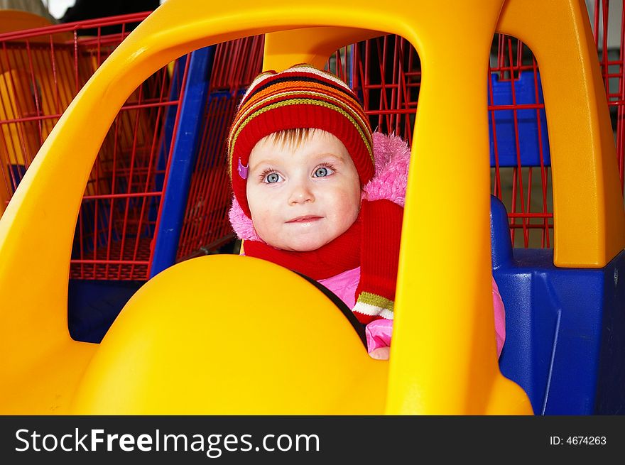 Little girl in the carriage in the form of the machine in a supermarket. Little girl in the carriage in the form of the machine in a supermarket