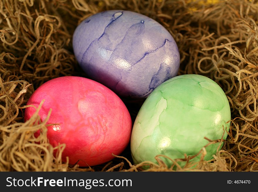 Three colorful pastel Easter Eggs in a basket.