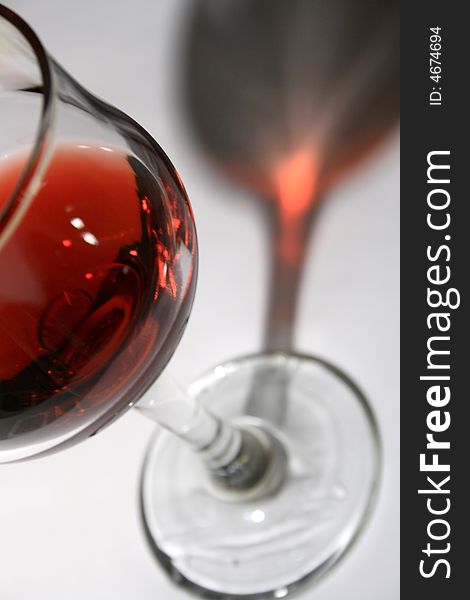 Goblet of red wine with long dark shadow on light-gray background. Goblet of red wine with long dark shadow on light-gray background