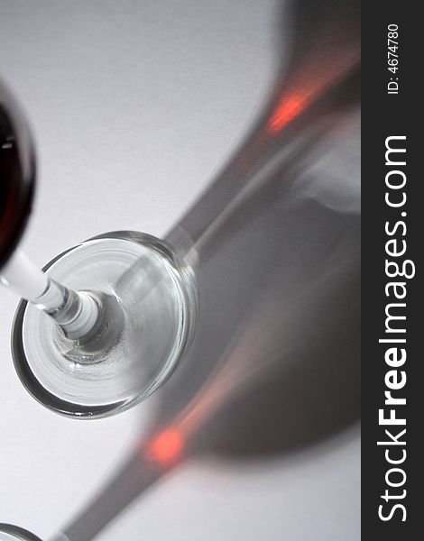 Goblet of red wine with long dark shadow on light-gray background. Goblet of red wine with long dark shadow on light-gray background
