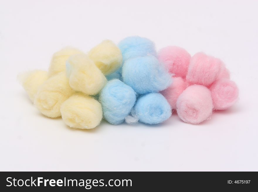 Yellow, blue and pink hygienic cotton balls isolated on a white background