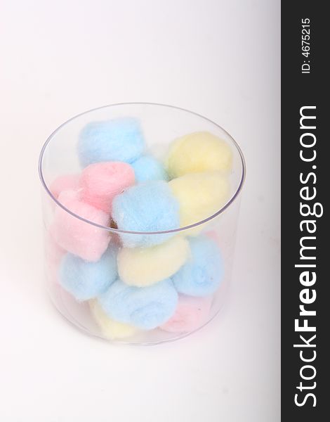 Blue and pink hygienic cotton balls in a glass canister isolated on a white background
