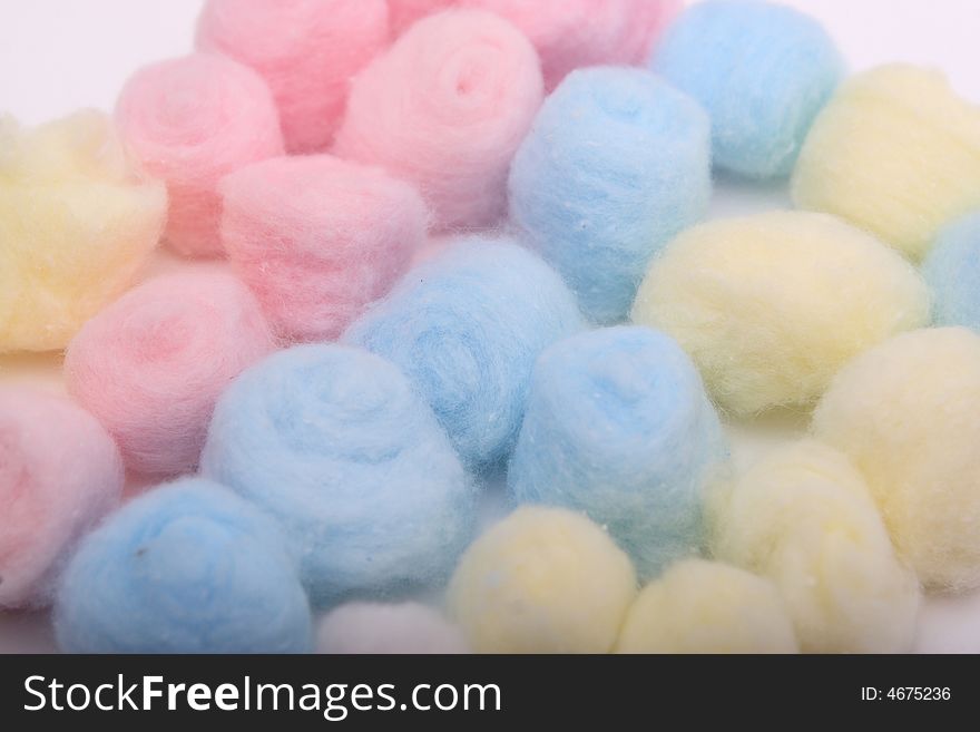 Yellow, blue and pink hygienic cotton balls in rows isolated on a white background