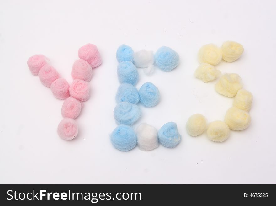 Word yes with blue, yellow and pink hygienic cotton balls isolated on a white background. Word yes with blue, yellow and pink hygienic cotton balls isolated on a white background