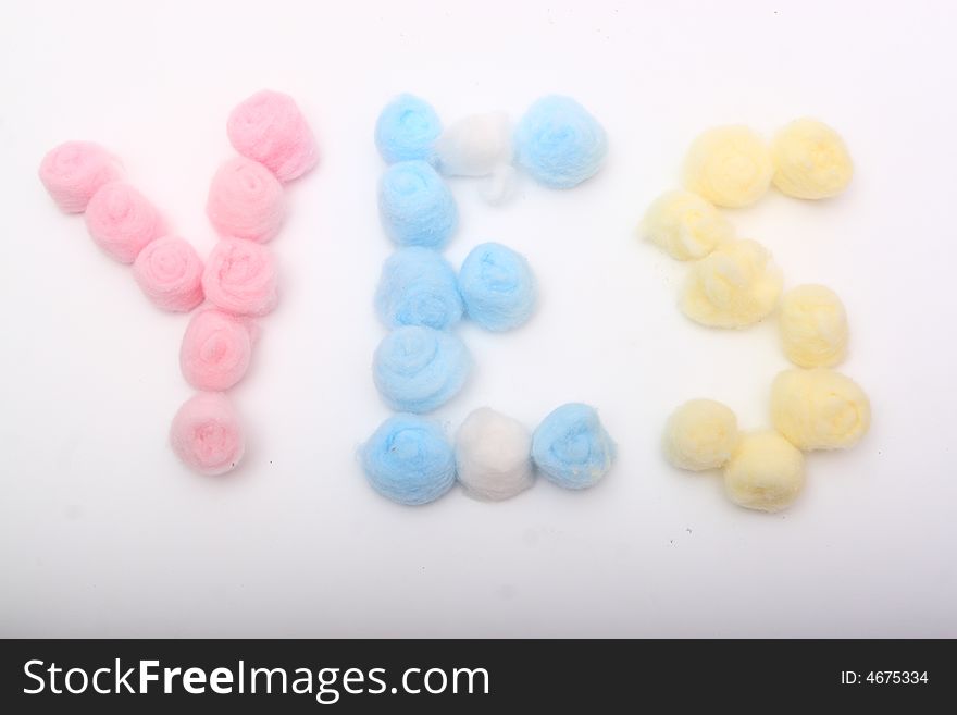 Word yes with blue, yellow and pink hygienic cotton balls isolated on a white background. Word yes with blue, yellow and pink hygienic cotton balls isolated on a white background