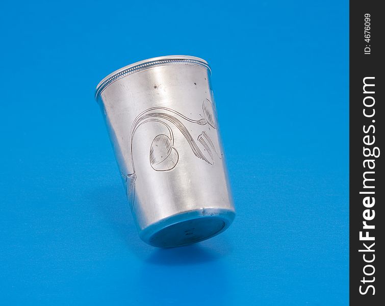 Vintage silver small drinking vessel with engraving over blue background