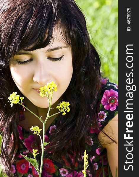 Young woman smelling yellow flower, green background