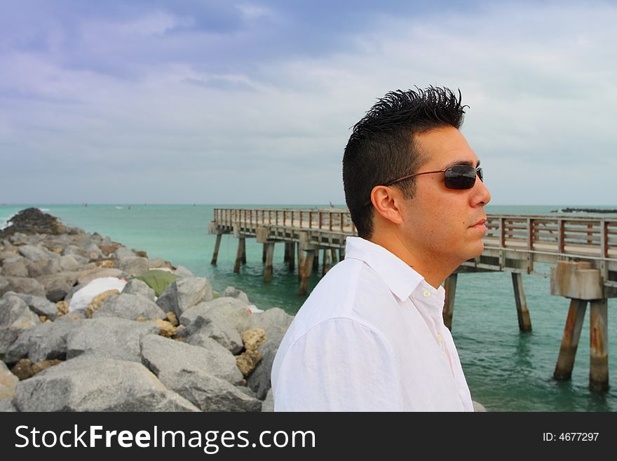 Man standing on the rocks near a pier at the beach. Man standing on the rocks near a pier at the beach.