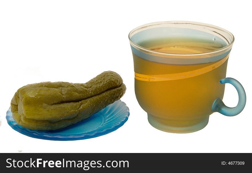 Glass mug with tea and a cucumber on a plate on a white background. Photo.