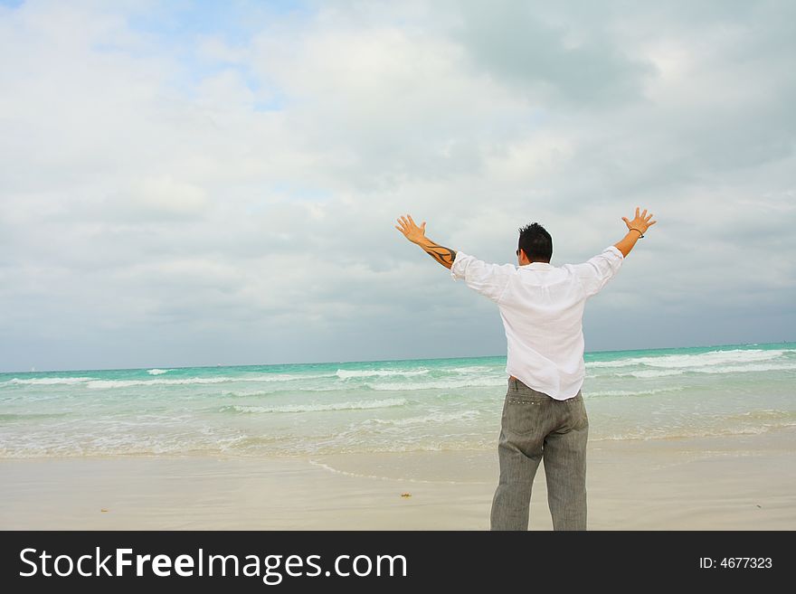 Man with arms extended facing the ocean. Man with arms extended facing the ocean