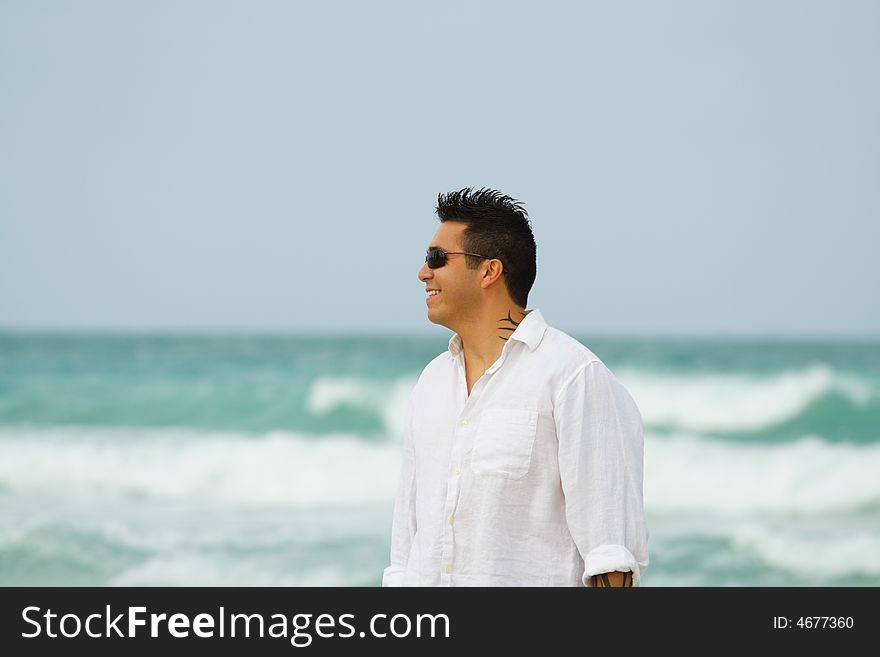 Happy young man smiling with blue ocean in th background. Happy young man smiling with blue ocean in th background.