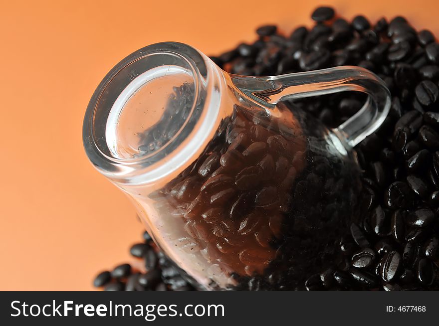 Transparent glass coffe cup up side down with coffe beans isolated on orange. Transparent glass coffe cup up side down with coffe beans isolated on orange