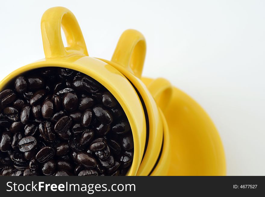 Three yellow cups with coffe beans isolated on white