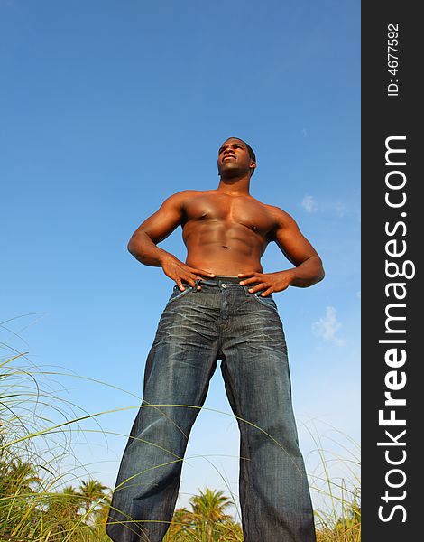 Tall bodybuilder wearing jeans and standing outside.