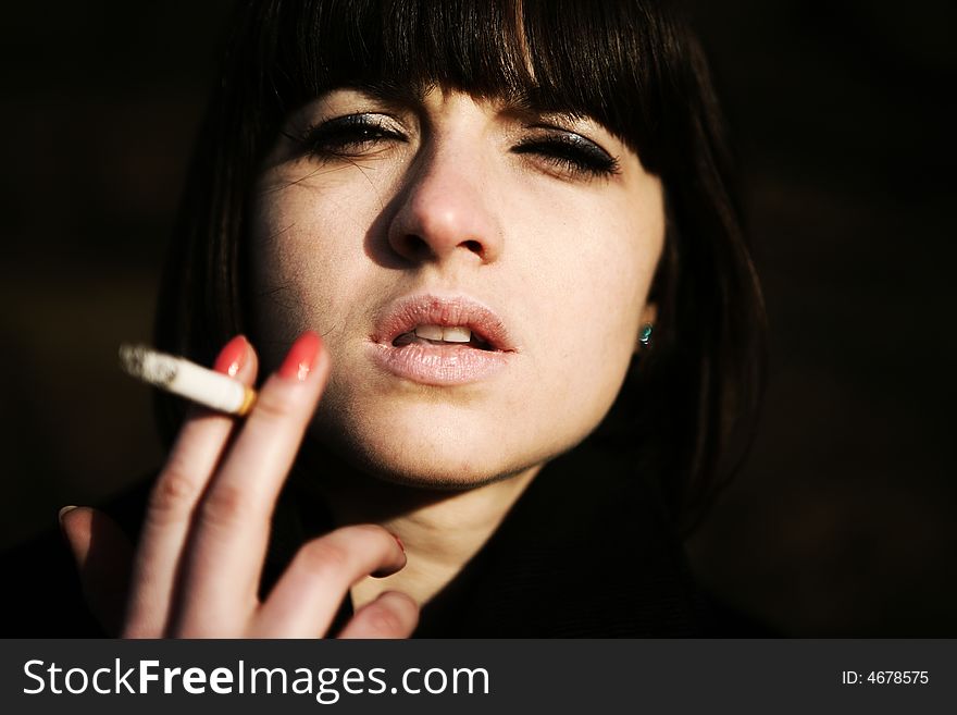 Young girl looking at the camera with a cigarette in her hand. Young girl looking at the camera with a cigarette in her hand