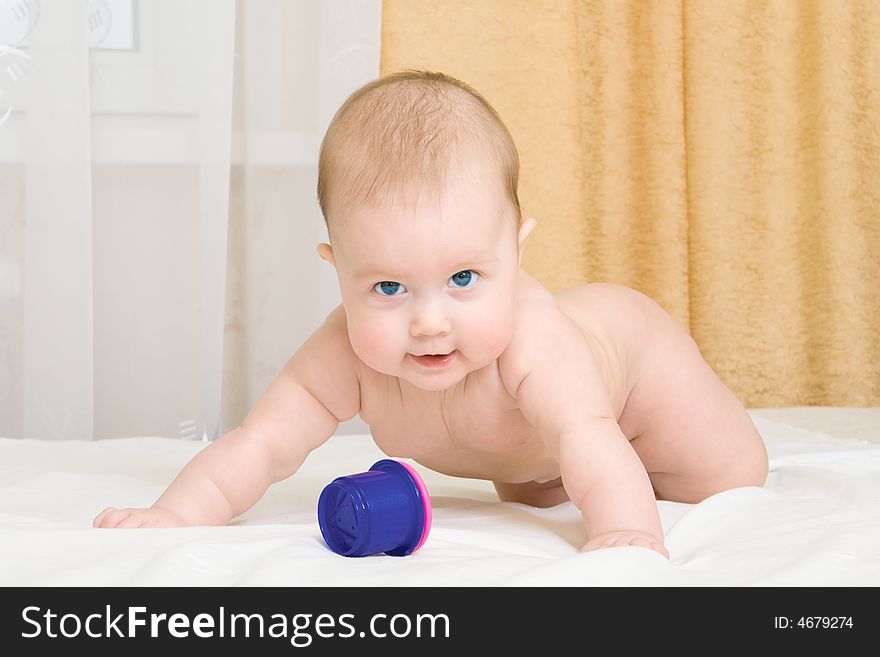 Small baby with toy on bed at home