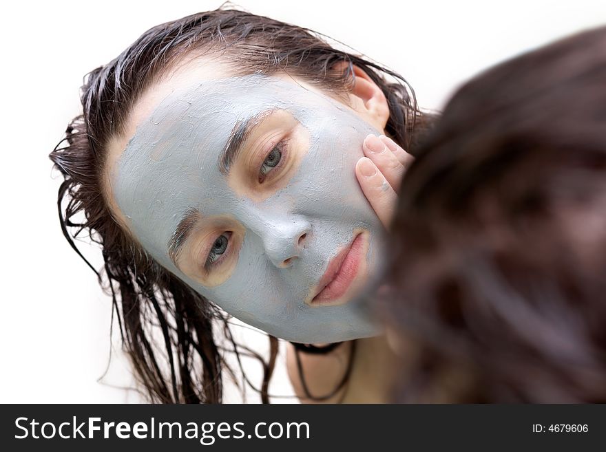 A girl putting a mud mask on her face