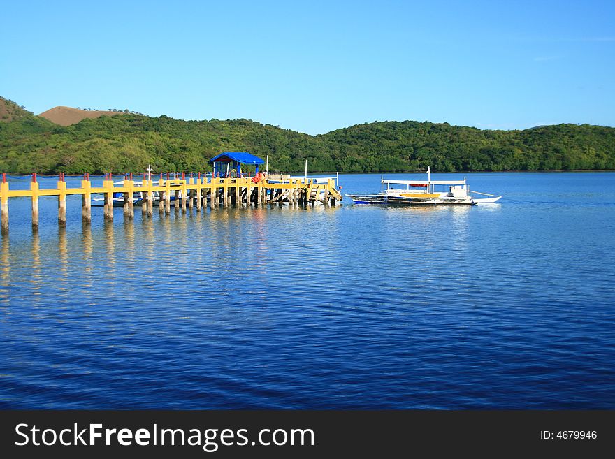 A pier from a resort leading to a boat. A pier from a resort leading to a boat