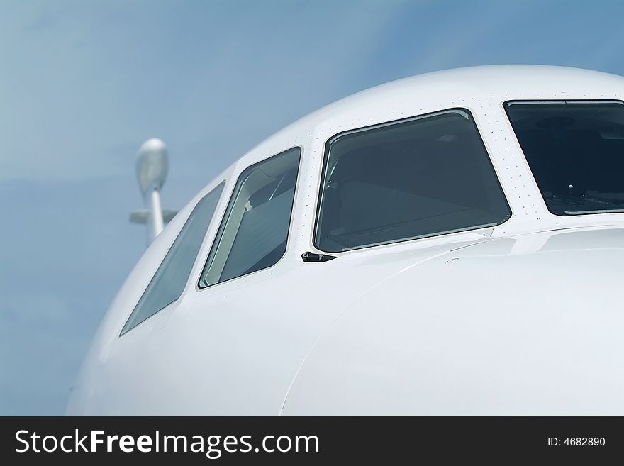 Front detail with cocpit windows of white business-jet. Shallow depth of field. Front detail with cocpit windows of white business-jet. Shallow depth of field.