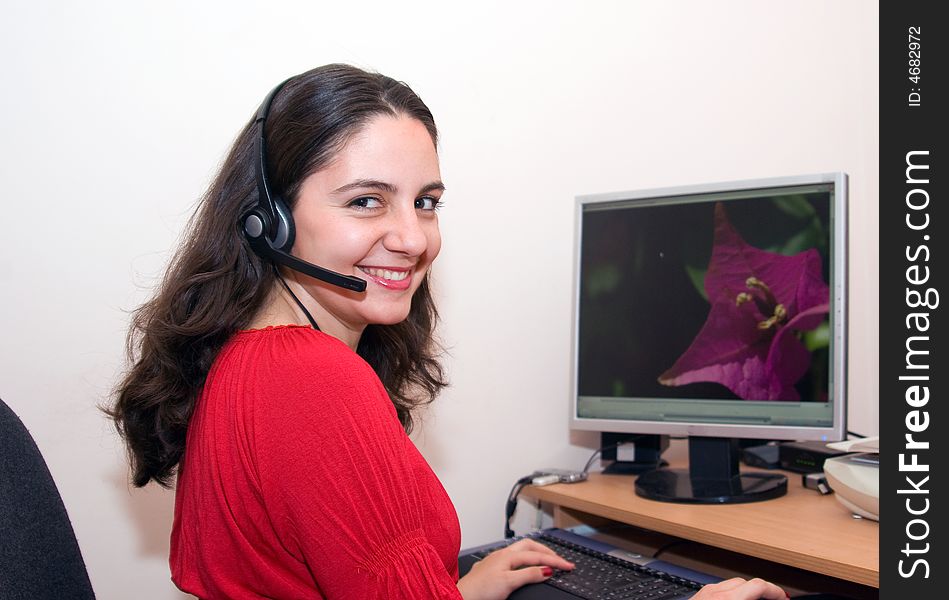 A girl, sitting at her desktop, looking very happy, smiling. A girl, sitting at her desktop, looking very happy, smiling