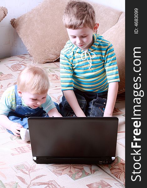 Two small boys together look at the screen of a laptop. Two small boys together look at the screen of a laptop