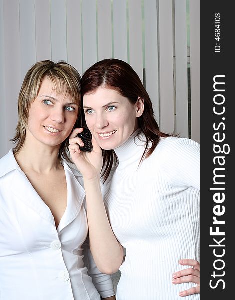 Two girls at office cost and consider a mobile phone