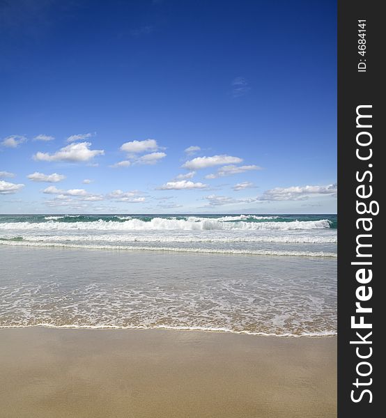 A golden sandy beach lapped by a gentle incoming Atlantic tide. Includes copy space.