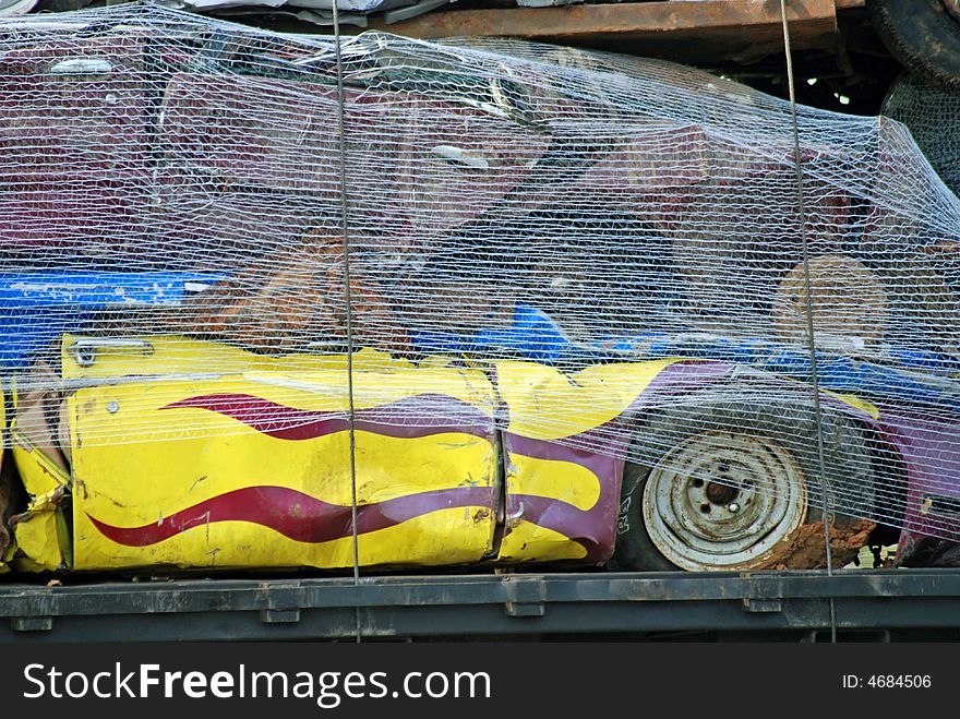 These vehicles have been scrapped as they are strapped and netted on the back of this trailer. The racing flames have been retired and were salvaged, crushed and on the way to be recycled. These vehicles have been scrapped as they are strapped and netted on the back of this trailer. The racing flames have been retired and were salvaged, crushed and on the way to be recycled.