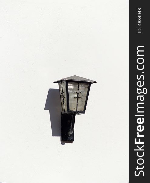 A minimalistic metallic street lamp on a white wall. A minimalistic metallic street lamp on a white wall